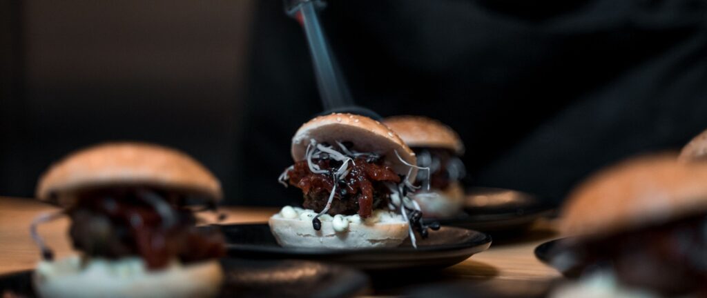 Vegane Mini-Burger mit Sprossen und Chutney auf schwarzen Tellern bei einem Dinner-Event