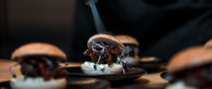 Vegane Mini-Burger mit Sprossen und Chutney auf schwarzen Tellern bei einem Dinner-Event